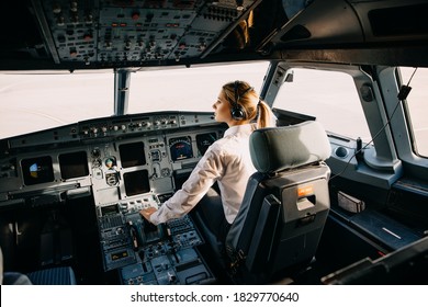 Confident woman pilot flying a commercial aircraft, sitting in cockpit
