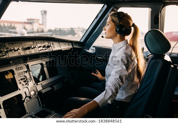 Confident woman pilot flying a commercial\
aircraft, sitting in\
cockpit.