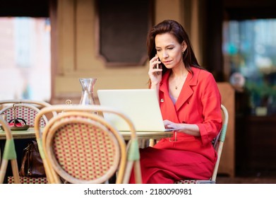 Confident Woman Sitting At The Cafe Behind Her Laptop And Having A Phone Call While Working Online.