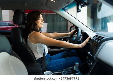 Confident woman smiling as she drives her car while feeling the cold air from her air conditioning - Powered by Shutterstock