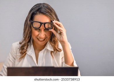 Confident Woman Smiling While Adjusting Glasses During Laptop Work - Powered by Shutterstock