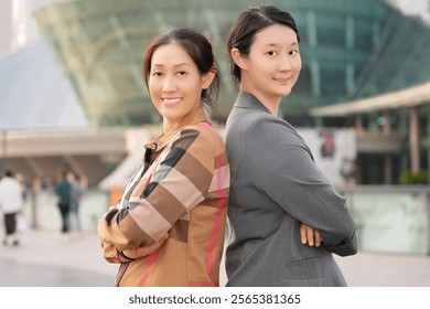 Confident Women in Professional Attire Back-to-Back in Urban Setting - Powered by Shutterstock