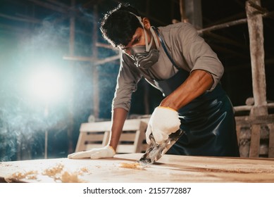 Confident wood worker expert. Young man working at factory. Skilled carpenter cutting a piece of wood in his woodwork workshop
