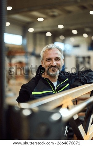 Confident worker posing in an industrial environment with a relaxed and satisfied expression.