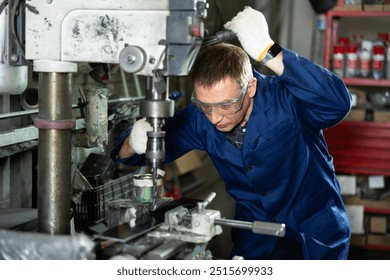 Confident workman drilling metal parts on stationary machine in metalworking workshop - Powered by Shutterstock