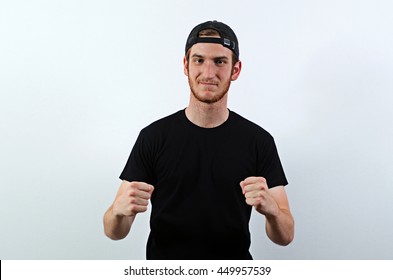 Confident Young Adult Male In Dark T-Shirt And Baseball Hat Worn Backwards