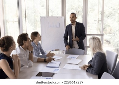 Confident young African American speaker man presenting marketing report, educating seminar, training employees interns. Business group talking, brainstorming at meeting table, discussing teamwork - Powered by Shutterstock
