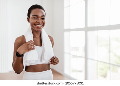 Confident young African American woman in white sportswear standing with towel near window, free copy space background. Portrait of happy professional coach prepare for workout training in sport club - Powered by Shutterstock