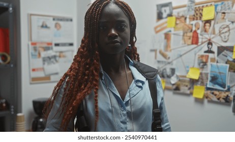 A confident young african american woman detective stands in her office, surrounded by investigation evidence. - Powered by Shutterstock