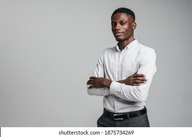 Confident Young African Man Wearing Smart White Shirt Standing Isolated Over Gray Background, Arms Folded