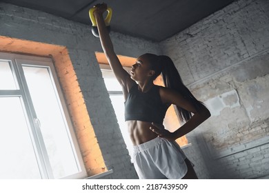 Confident young African woman lifting kettlebell while exercising in gym - Powered by Shutterstock