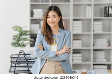 Confident young Asian business woman sitting with arms crossed smiling looking at camera in the office	 - Shutterstock ID 2291046343