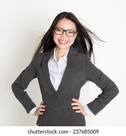 Confident Young Asian Business Woman Smiling At Camera, Standing On Plain Background.