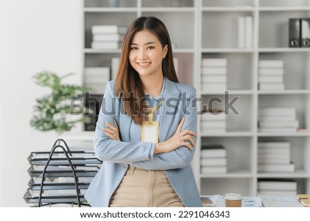 Confident young Asian business woman sitting with arms crossed smiling looking at camera in the office	