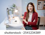 Confident young asian businesswoman smiling with arms crossed while sitting at her desk in a modern office, working late at night