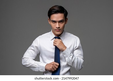 Confident young Asian male entrepreneur in white shirt standing on gray isolated studio background - Shutterstock ID 2147992047