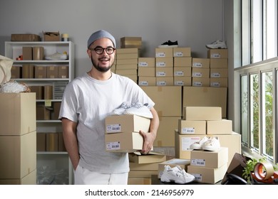 Confident young Asian man retail seller, entrepreneur, online store drop shipping small business owner looking at camera standing in delivery shipping warehouse with parcel boxes. - Shutterstock ID 2146956979