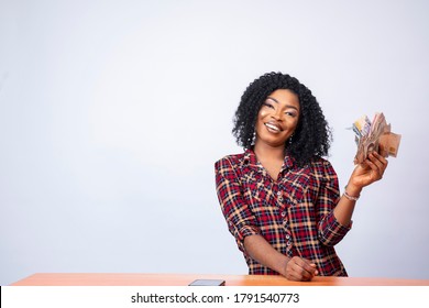 confident young black lady sitting and holding a wad of cash