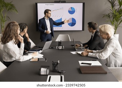 Confident young business leader man presenting marketing statistic report to partners, investors, selling startup project on meeting, negotiations, showing graphs on electronic display - Powered by Shutterstock