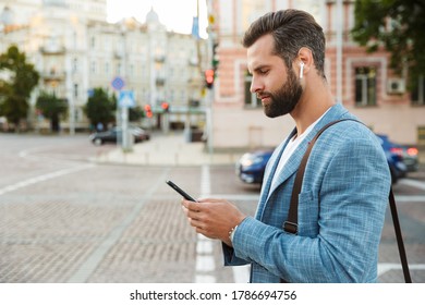 Confident Young Business Man Walking Outdoors With Mobile Phone And Earphones