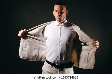 Confident Young Business Man In White Suit With The Jacket Open On Black Background.