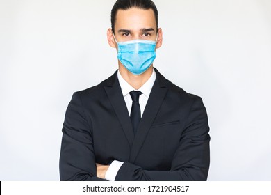 Confident young businessman with arms crossed wearing a blue virus protective medical mask. Isolated portrait looking at the camera. - Powered by Shutterstock