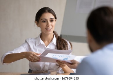 Confident young businesswoman lead meeting share handout materials to colleagues, smiling millennial female CEO or team leader brainstorm head team briefing with coworkers in boardroom - Shutterstock ID 1679694655
