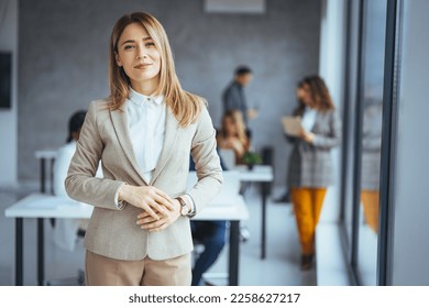 Confident young businesswoman standing in a modern office. Portrait of a businesswoman standing in the office. One Happy Pretty Business Woman Standing in office and looking at camera with smile.