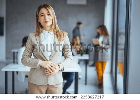 Confident young businesswoman standing in a modern office. Portrait of a businesswoman standing in the office. One Happy Pretty Business Woman Standing in office and looking at camera with smile.