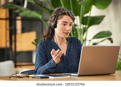 Confident young businesswoman wearing headphones and discussing project details with clients on video call. Skilled woman worker with headphones conducting online meeting with colleagues. - Shutterstock ID 1855133746