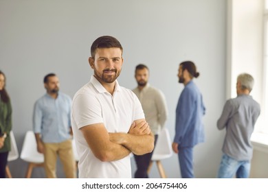 Confident Young Caucasian Businessman Or Entrepreneur Stand Forefront In Company Business Office. Smiling Successful Millennial Generation Z Male Employee Or Worker Show Leadership. Career Concept.