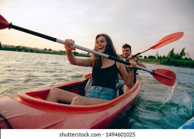 Confident young caucasian couple kayaking on river together with sunset in the backgrounds. Having fun in leisure activity. Romantic and happy woman and man on the kayak. Sport, relations concept. - Powered by Shutterstock