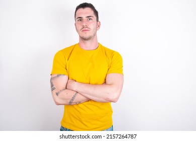 Confident Young caucasian man wearing yellow t-shirt over white background with arms crossed looking to the camera - Shutterstock ID 2157264787