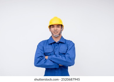 Confident young construction worker wearing blue coveralls and a yellow hard hat, standing against a white background, embodying professionalism and safety. - Powered by Shutterstock