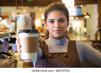 Confident Young Female Coffee Barista Giving Cup