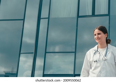 Confident Young Female Doctor Standing Near A Large Hospital Building .