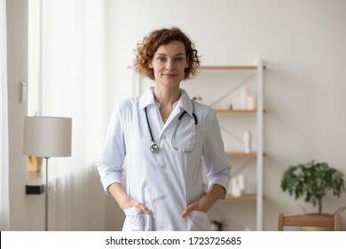 Confident young female physician standing in medical office. Proud professional woman doctor therapist looking at camera. Portrait of lady general practitioner wearing white coat and stethoscope. - Shutterstock ID 1723725685