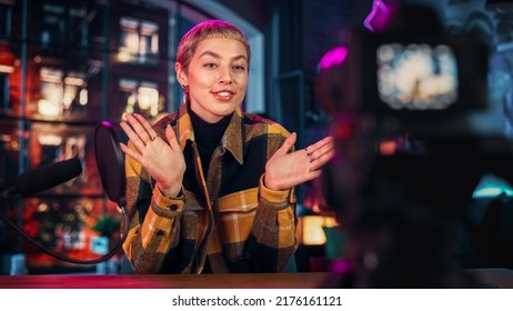 Confident Young Female Talking Into Microphone While Recording Radio Show from Her Loft Apartment. Happy Woman with Short Hair Talking on Camera and Recording Podcast Live on Social Media. - Powered by Shutterstock