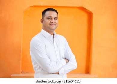 Joven indio de confianza con camisa blanca parado en brazos cruzados contra fondo naranja, Hombres asiáticos sonrientes y guapos con expresión positiva posando.