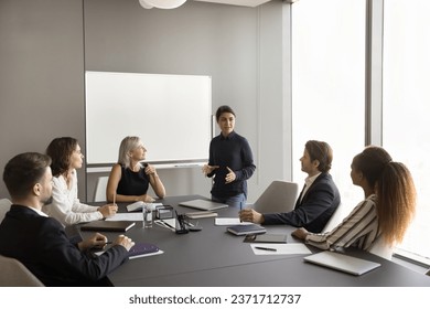 Confident young Indian manager presenting project report to diverse team, offering ideas, marketing strategy. Multiethnic colleagues with mature leader discussing cooperation - Powered by Shutterstock