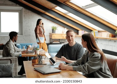 Confident young male employee pointing at tablet screen during explanation of online data to female colleague in coworking space - Shutterstock ID 2330150843