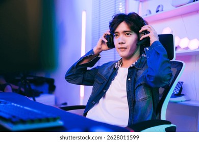Confident young male gamer adjusts his headset while sitting in a modern gaming setup with neon lighting. Captures preparation, focus, and digital lifestyle in competitive gaming culture.