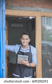 Confident young male with tablet standing in front of his business property - Shutterstock ID 609200291