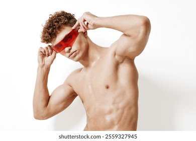 Confident young man with curly hair posing with red sunglasses, showcasing a stylish look. Fashion and self-expression concept with minimalist background. - Powered by Shutterstock