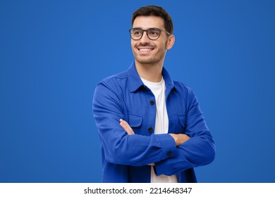 Confident young man looking away, standing with crossed arms isolated on blue - Powered by Shutterstock