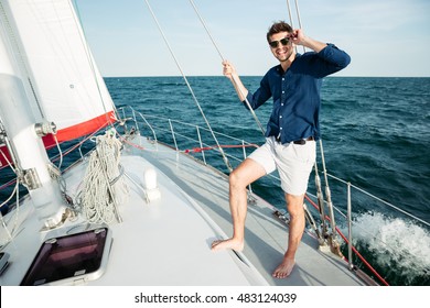 Confident young man looking forward and smiling while standing on the yacht - Powered by Shutterstock