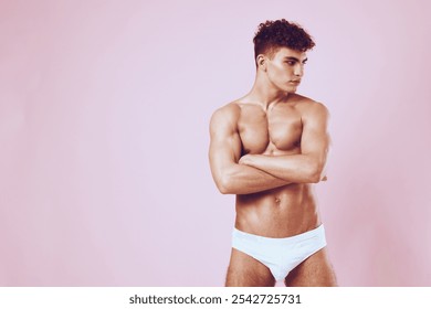 Confident young man posing against a pink background, showcasing toned physique with arms crossed. Fitness and body positivity concept. - Powered by Shutterstock