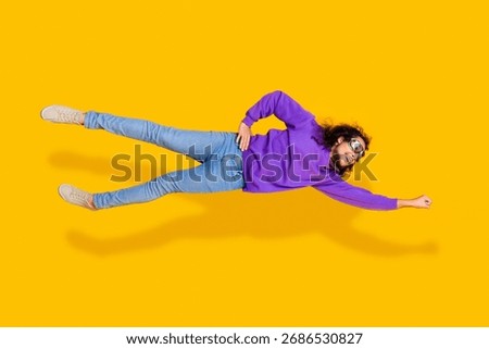 Confident young man posing in dynamic flying position with vibrant yellow background