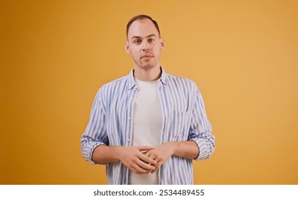 Confident young man stands calm and straight on orange background. People emotions, portrait, mood and reflection, social interaction concept - Powered by Shutterstock