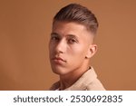 Confident young man with stylish haircut on brown background